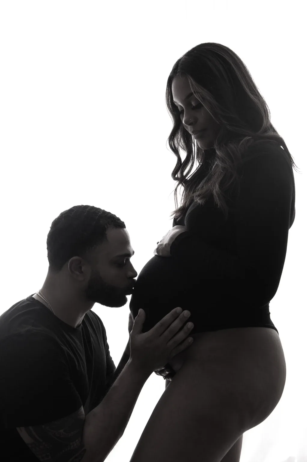 Anthony kissing the baby bump in a maternity portrait with Krystiana